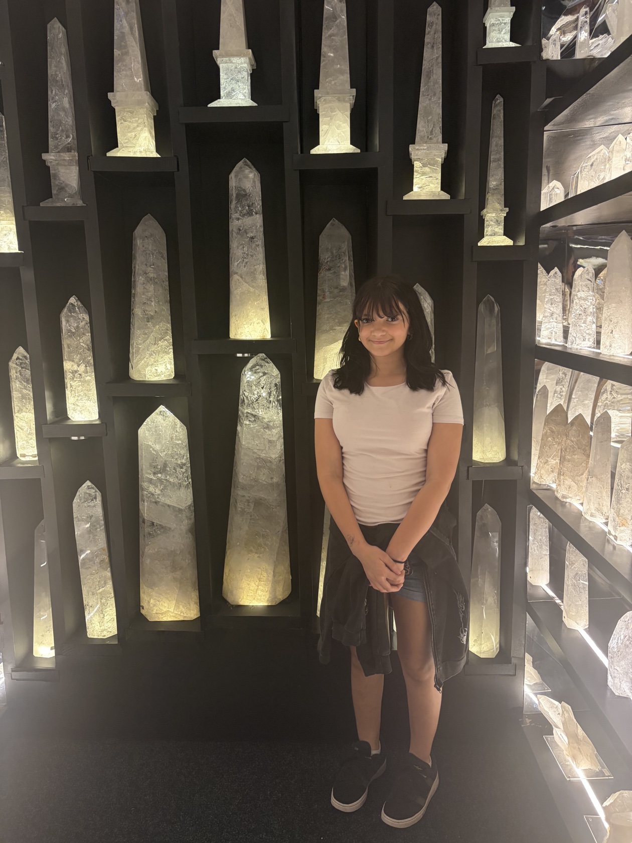 Lillyana standing calmly among tall, softly glowing crystals